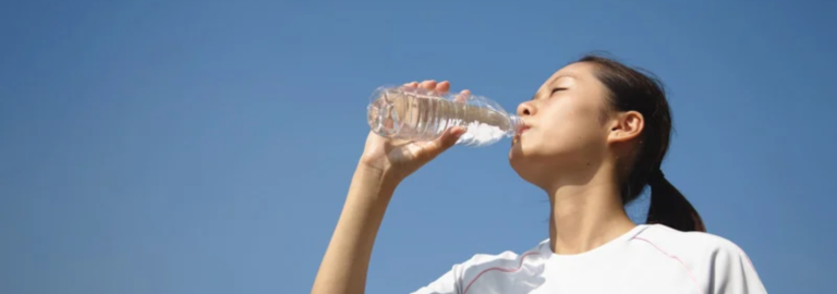 Individual sipping warm water during a winter workout to maintain hydration.