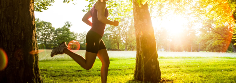 A woman running in a sunny green park, symbolizing motivation, growth, and consistency during the spring season.