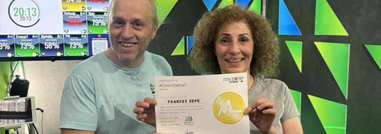 rances Sepe smiling and holding a certificate of achievement inside AB Health & Fitness gym.