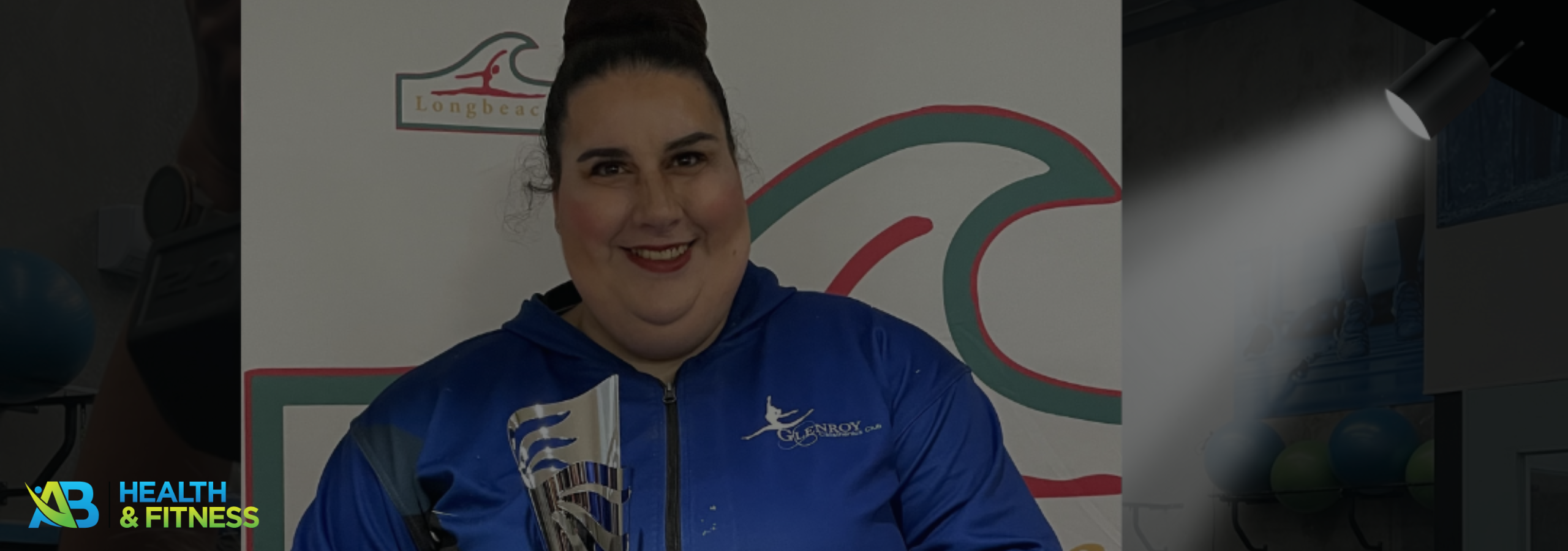 Jasmine holding a trophy and smiling, celebrating her transformation at AB Health & Fitness.