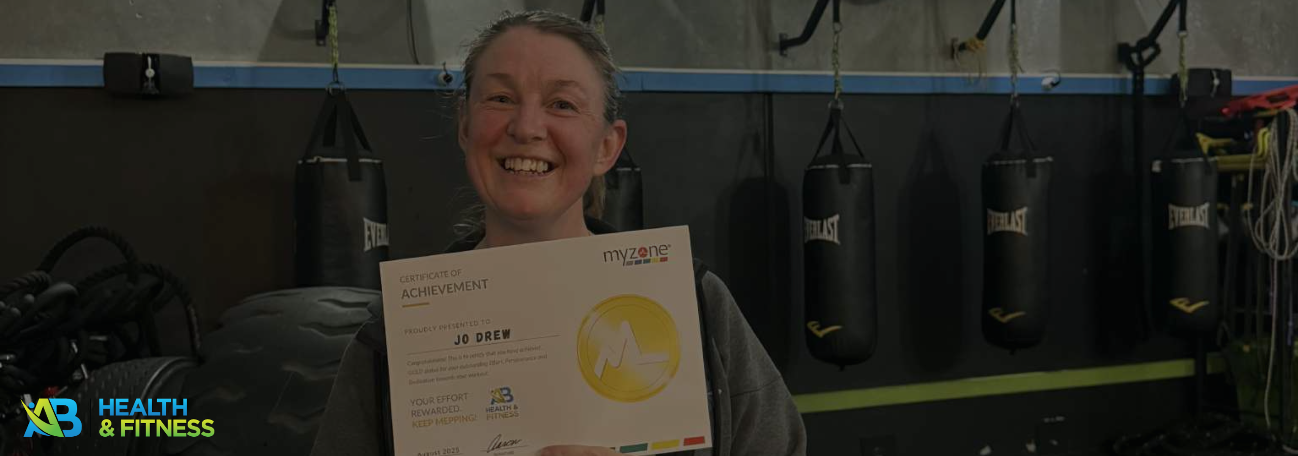 Joanne holding a certificate of recognition for her effort and commitment at AB Health & Fitness gym